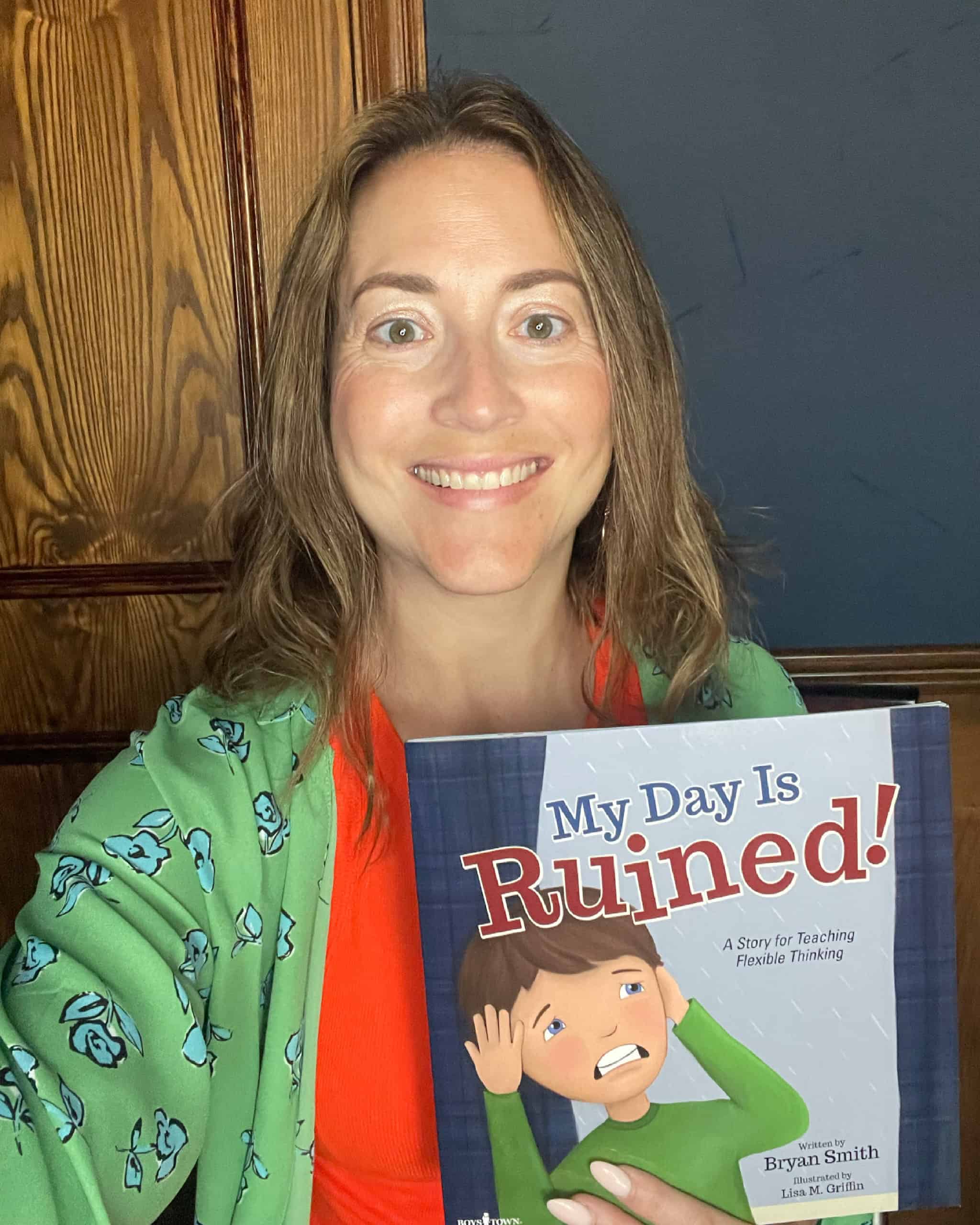 Jules holding a copy of the kids book My Day is Ruined!